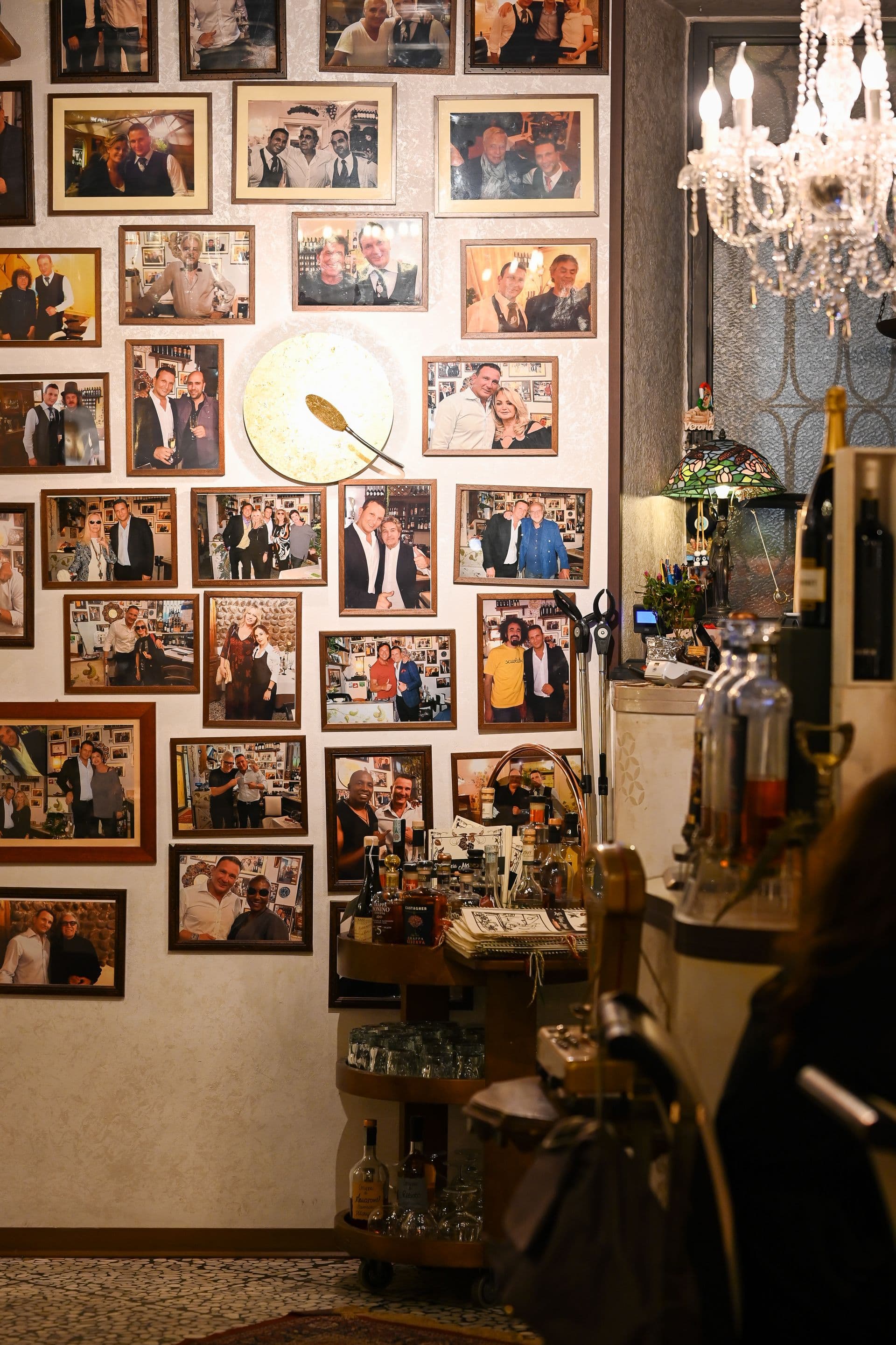 La parete con le foto degli ospiti celebri e il lampadario di cristallo de La Vecia Mescola
